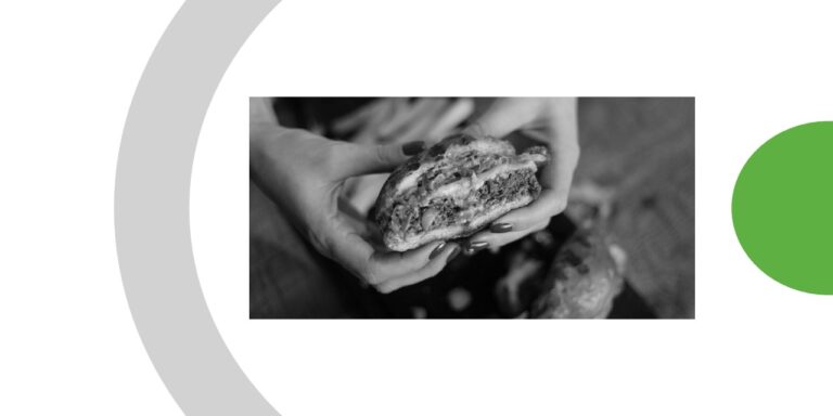 deux mains tenant un hamburger à moitié mangé