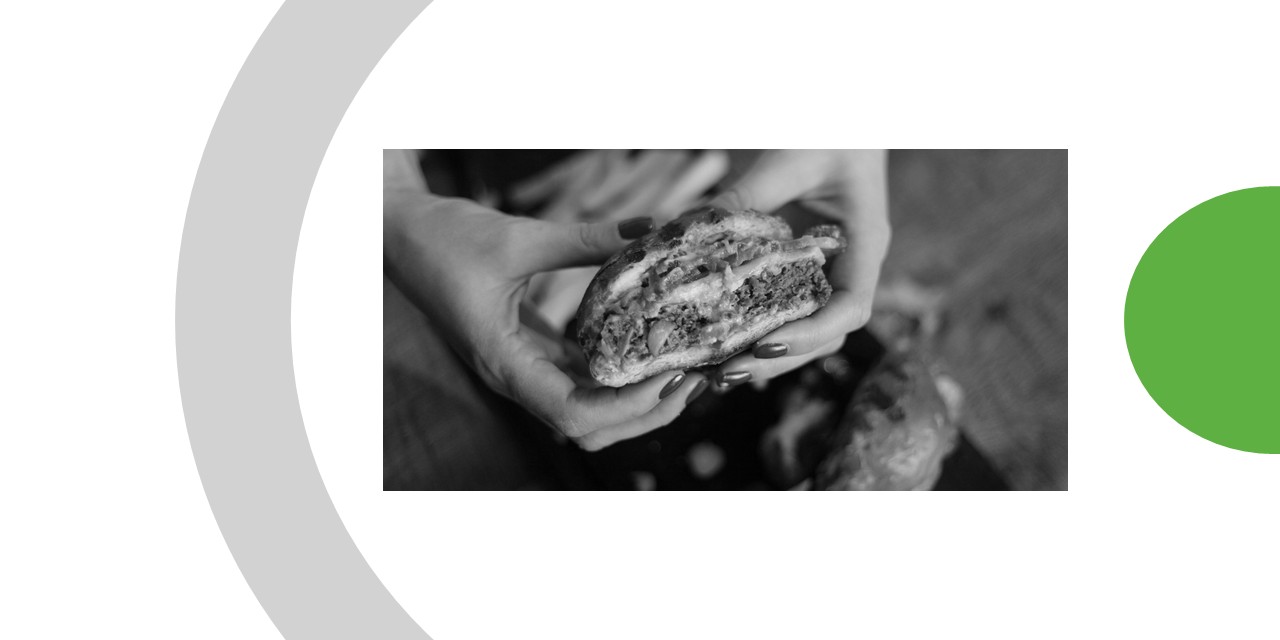 deux mains tenant un hamburger à moitié mangé